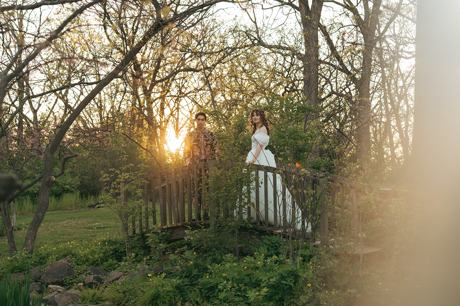 wedding couple stands on a bridge in their backyard