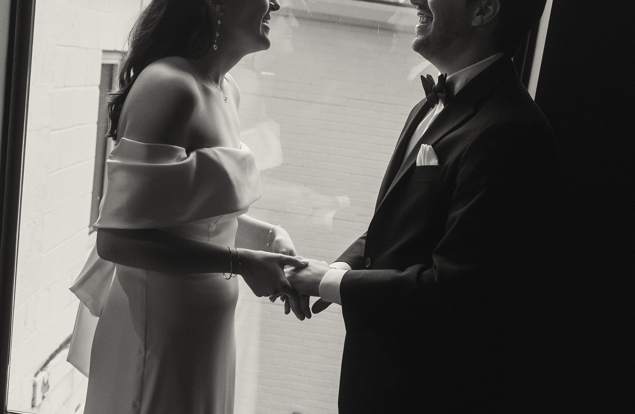 wedding couple stands laughing in front of a window at The Moxy hotel in Madison,WI